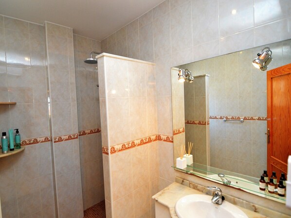 Un baño con ducha, lavamanos y espejo.