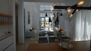 Una sala de estar moderna con una mesa de comedor de vidrio, un sofá y lámparas colgantes.