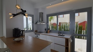 Una cocina moderna con una isla central, electrodomésticos integrados y amplias ventanas que ofrecen vistas al exterior.