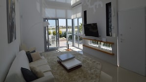 Un salón moderno con un ventanal grande, un televisor de pantalla plana y un sofá.