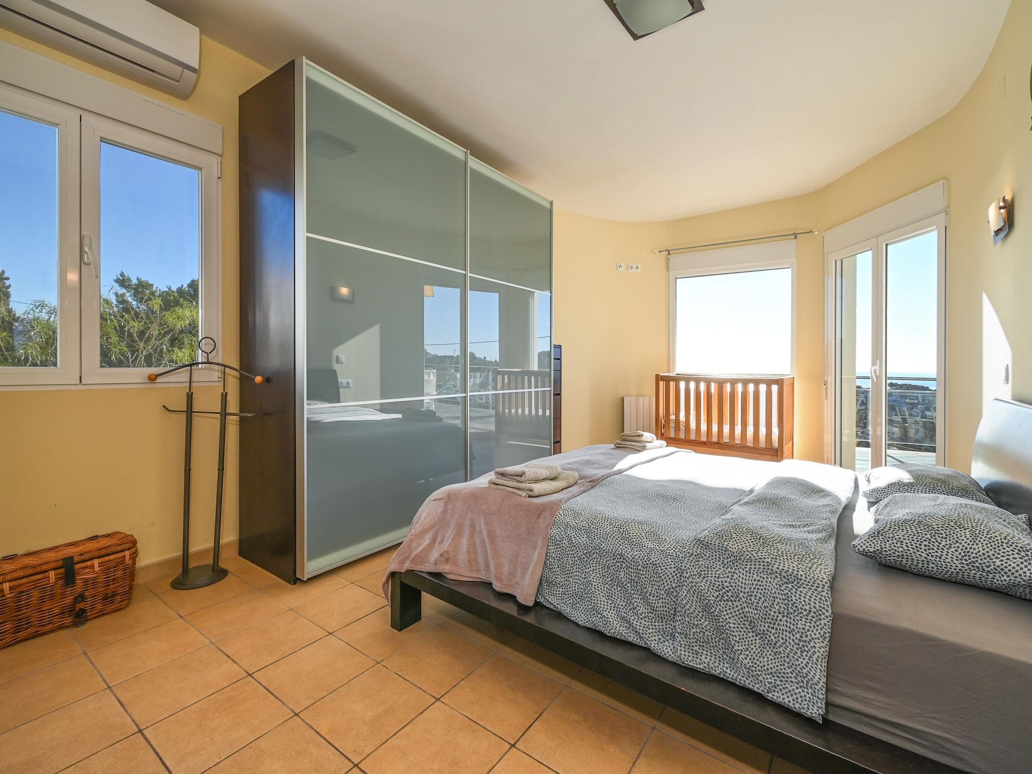 Une chambre à coucher avec un lit, une armoire, un balcon et une vue sur l’extérieur.