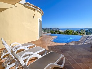 A pool area with lounge chairs, a clear view of the sea, and a tiled patio. - Villa in Moraira with Pool near Beach (Moraira)