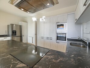 A modern kitchen with a built-in oven, a stainless steel refrigerator, and a black marble countertop. - Villa in Moraira with Pool near Beach (Moraira)