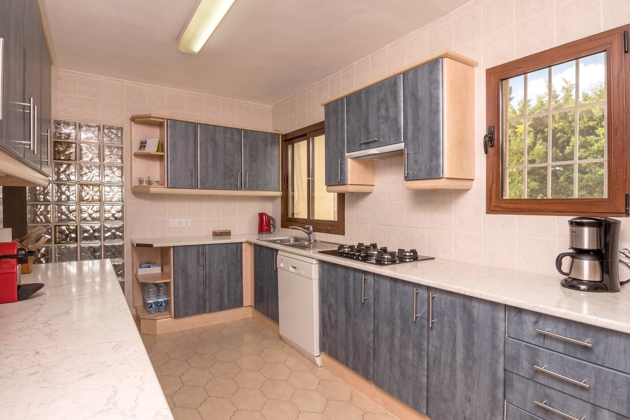 A modern kitchen with grey cabinets, a white countertop, a built-in dishwasher, a gas stove, and a coffee maker.