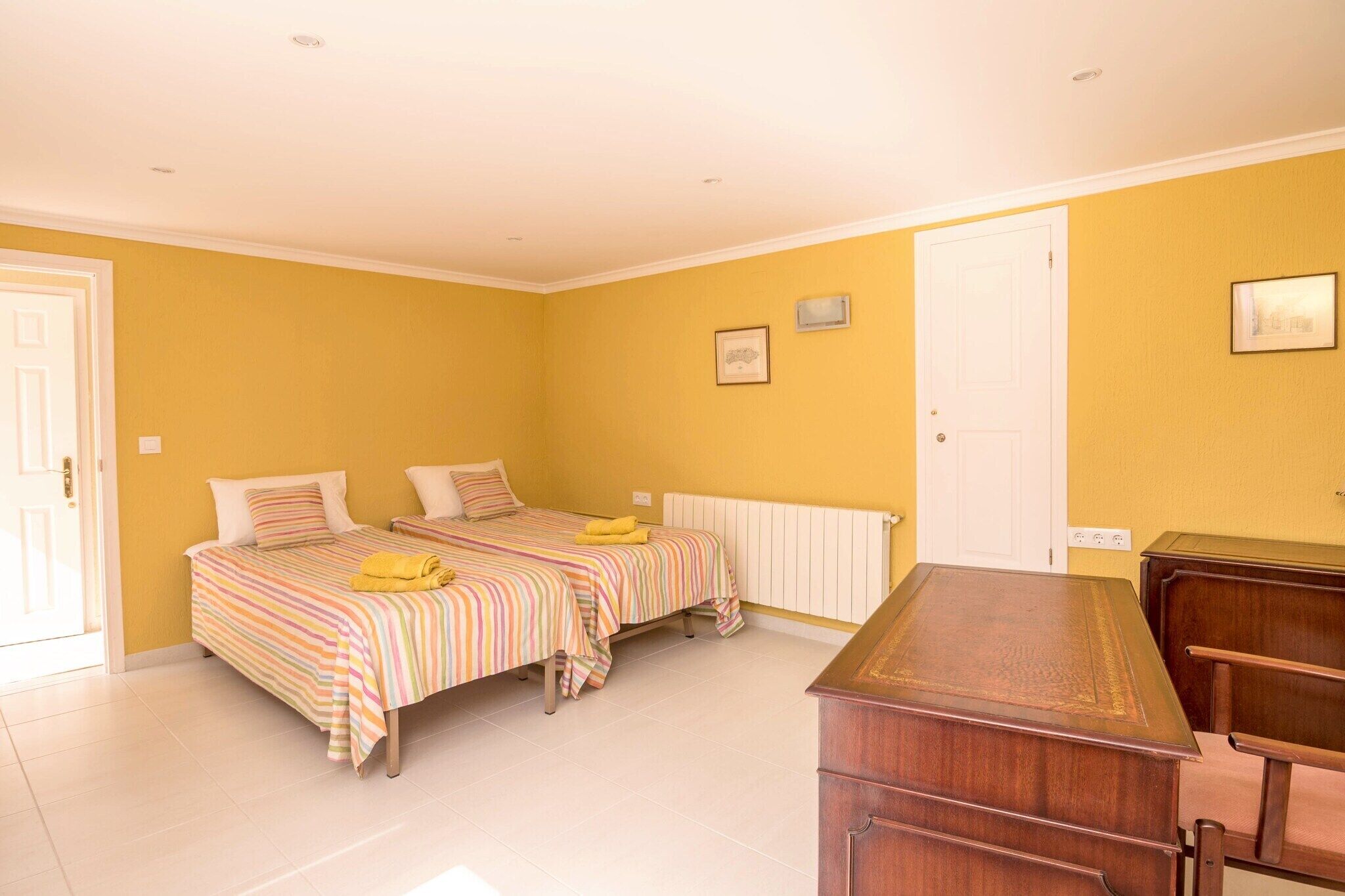 Une chambre avec deux lits, une commode en bois et une porte blanche.