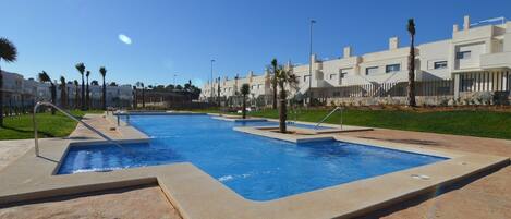 En swimmingpool med flere baner, omgivet af belagt areal og palmer.