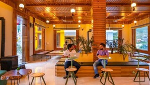 A wooden interior with seating areas, a fireplace, and large windows.