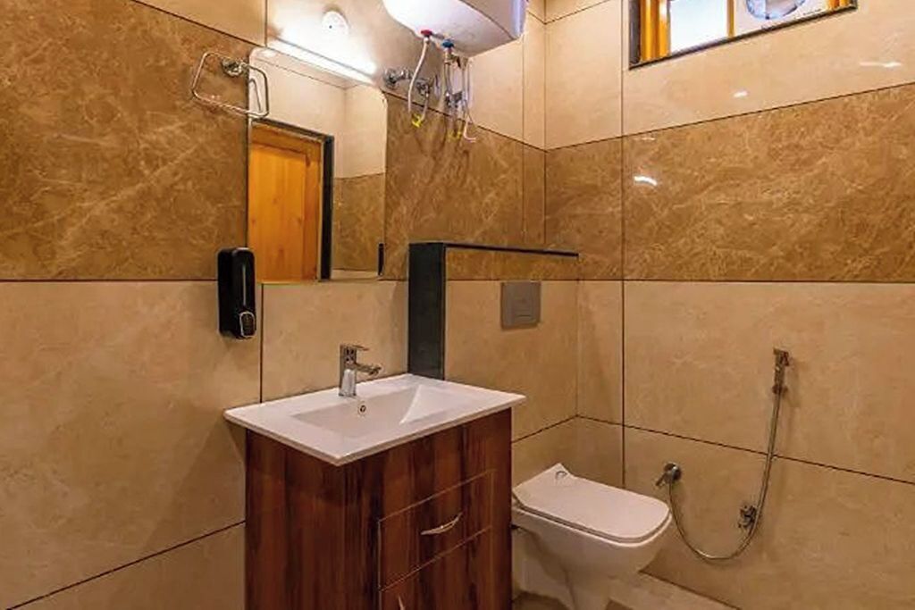 Un bagno con un mobiletto contenitore in legno, un lavandino bianco, un water e una doccia.