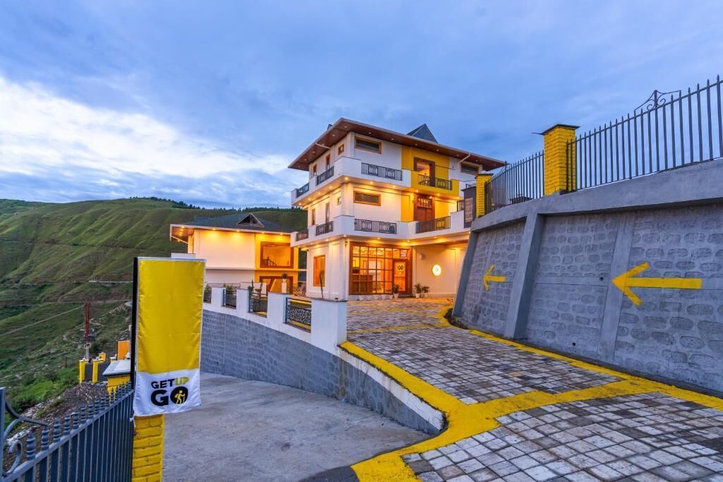 A multi-story hotel with a stone facade, a balcony, and a sign that reads "GET UP GO".
