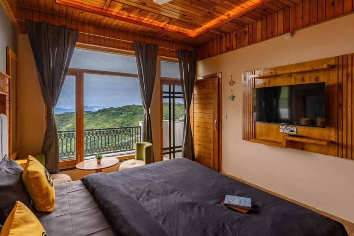 Quarto com cama, televisão, varanda e ventoinha no teto.