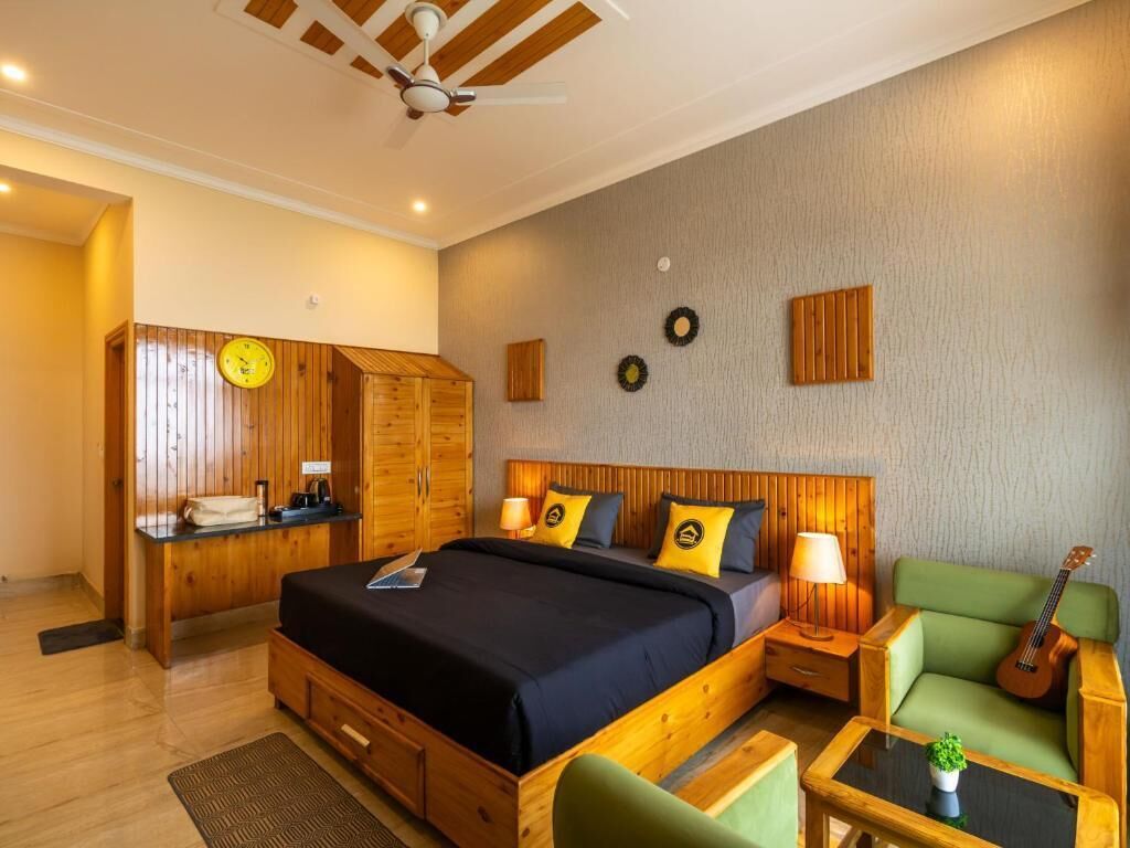 A bedroom with a wooden bed, a green sofa, a small table, a guitar, and a wall clock.