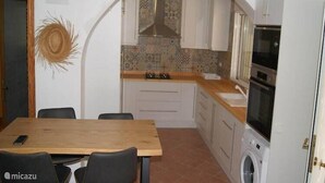 A compact kitchen with white cabinets, a wooden countertop, and a built-in washing machine.