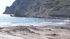 A rocky beach with a rocky cliff in the background.
