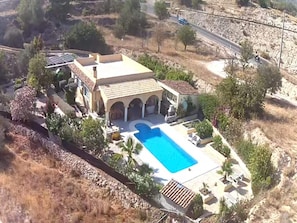 Une villa de style méditerranéen dotée d’une piscine, de fenêtres en arc de cercle et d’un jardin.