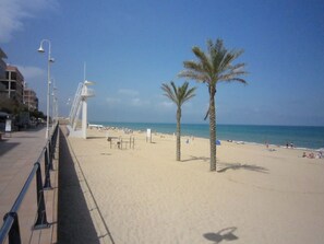 A beach with a walkway, palm trees, and a lifeguard tower. - Sunny Stay, Orihuela Costa (Orihuela Costa)