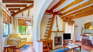 A cozy living room with a fireplace, wooden beams, and a dining area. - Sunny Family Villa, Calpe (Calpe)