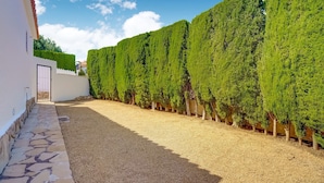 A gravel pathway flanked by neatly trimmed hedges and a white building with a tiled entrance. - Sunny Family Villa, Calpe (Calpe)