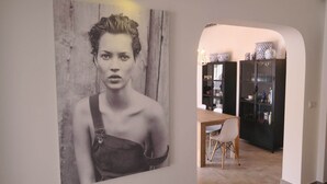 Une pièce comprenant un coin repas avec une table et des chaises en bois, un meuble noir avec des portes en verre et un luminaire fixé au mur.