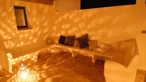 Un salon chaleureux avec un canapé, un luminaire décoratif et une étagère fixée au mur.