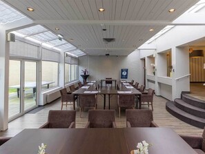 Conference room with a long table and comfortable seating, featuring large windows and a skylight.