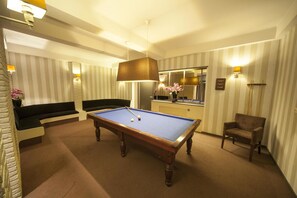 Relax in style with a pool table, sofa, and chair, surrounded by a large mirror and ambient lighting.