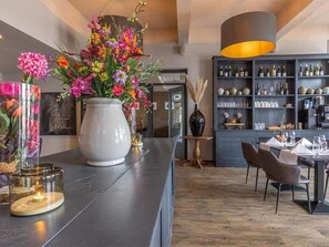 Enjoy a sophisticated atmosphere with a well-stocked wine and glass display, complemented by a beautiful floral arrangement.