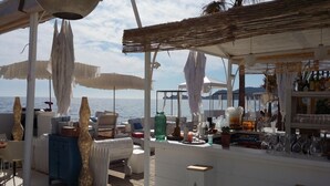 Un bar frente al mar con terraza, sombrillas y vistas al océano.