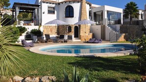 Una villa moderna con piscina, mobiliario exterior y fachada de piedra.