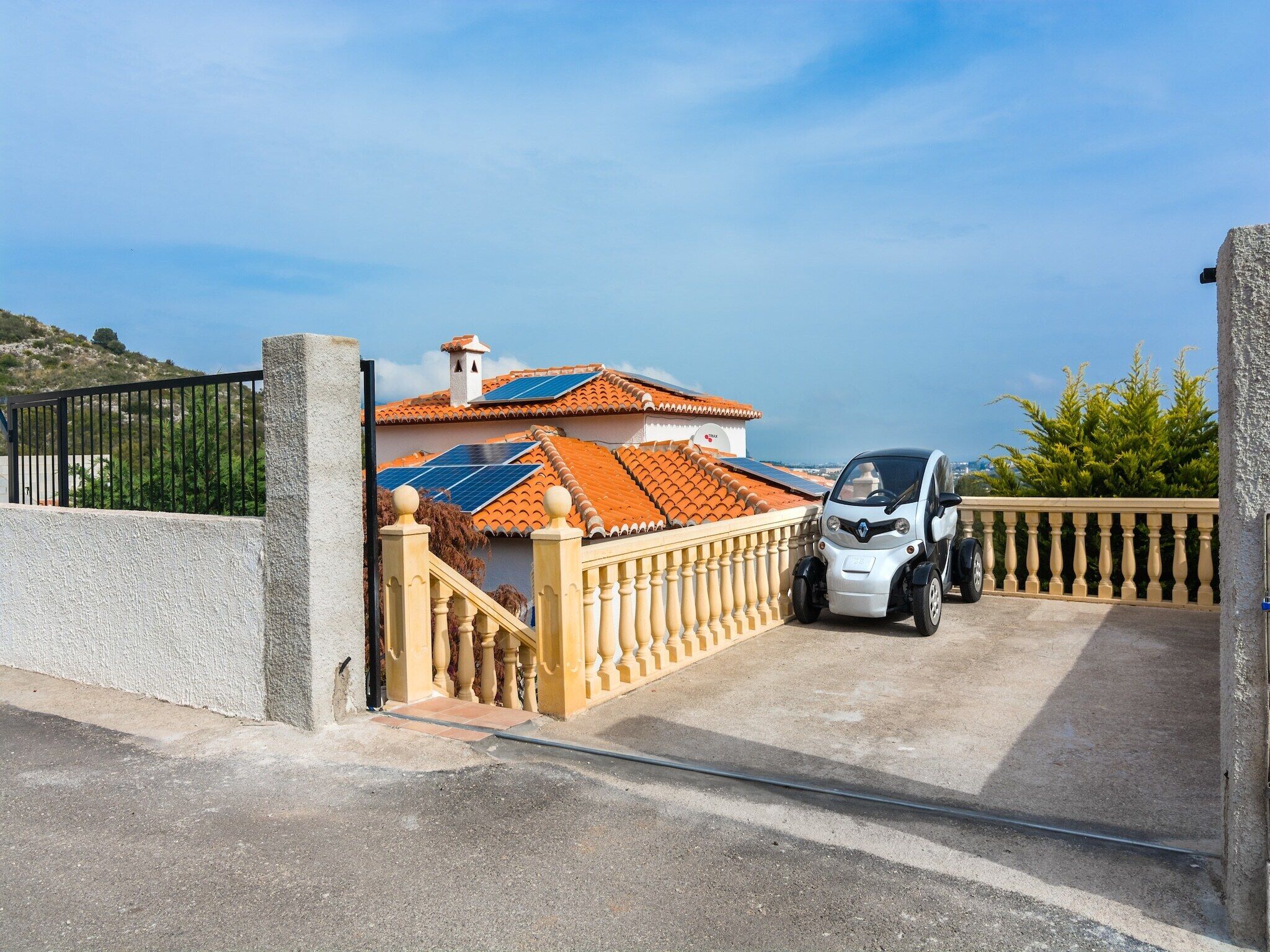 Il s’agit d’une propriété résidentielle dotée d’une entrée sécurisée par un portail, d’un toit équipé de panneaux solaires et d’une petite voiture garée à l’intérieur.