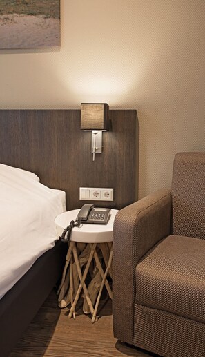 Relax in this inviting space with a comfortable bed, a small table for convenience, and a cozy armchair.