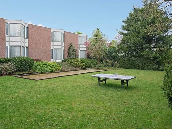 Enjoy a tranquil outdoor space with a lawn, ping pong table, and lush surroundings.