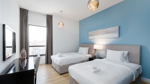 Une chambre d’hôtel avec deux lits, un bureau et une grande fenêtre.