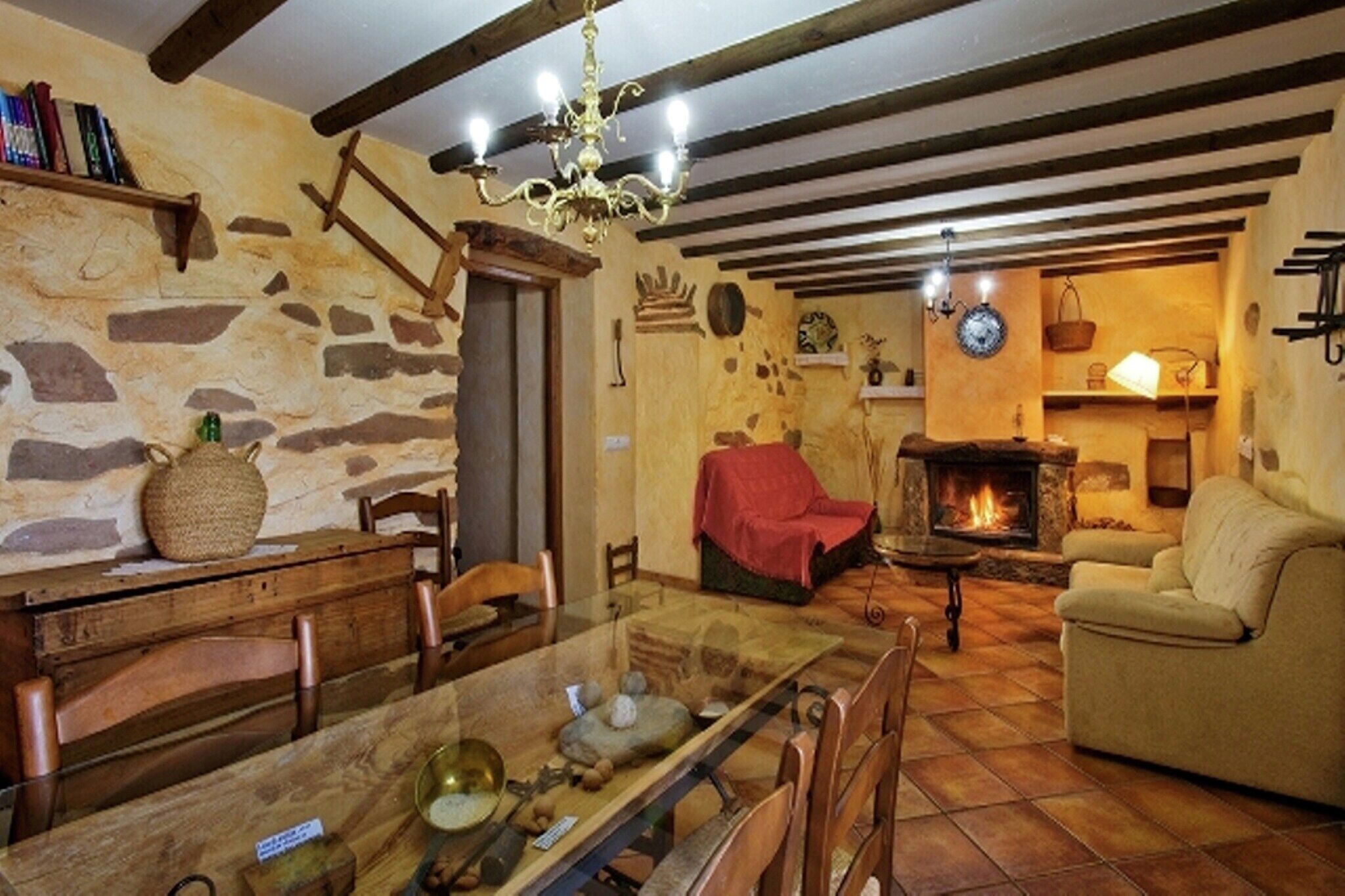 Ein rustikales Wohnzimmer mit einer Steinwand, Holzmöbeln, einem Kamin und einer Chandelüster.