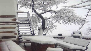 A snow-covered outdoor area with a stone bench, a wooden chair, and a staircase leading to a higher level. - Holiday Home in Laroya near centre (Laroya)