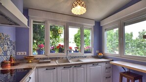 Cocina con armarios blancos, un lavamanos y ventana con vistas a un jardín.