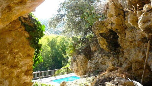 A natural rock formation with a pool and a wooden deck.