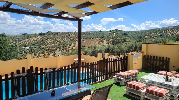 Um pátio com piscina, área de estar ao ar livre e vista para uma paisagem montanhosa.
