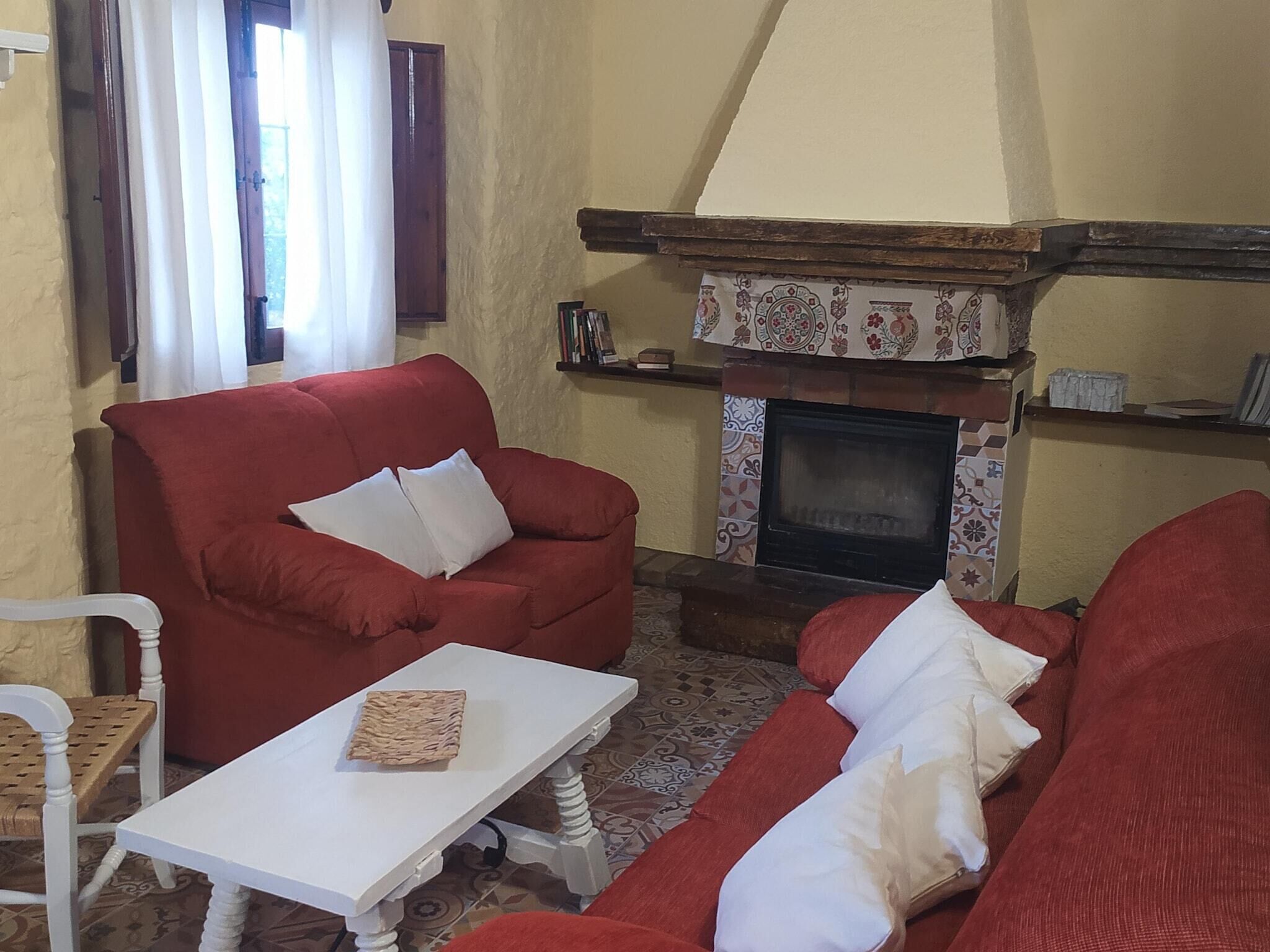 Una sala de estar con chimenea, sofás rojos, una mesa blanca y baldosas estampadas.