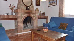 A living room with a brick fireplace, a blue sofa, a wooden coffee table, and a glass vase with flowers.