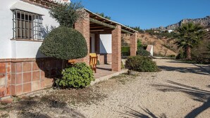 A house with a patio, a small garden, and a view of a hilly landscape. - Spacious Cottage with Pool (Villanueva de la Concepción)