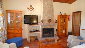 A living room with a fireplace, television, and wooden cabinets.
