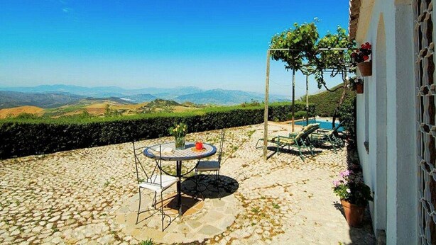 A patio with a table and chairs, a small pool, and a view of distant hills. - Cottage in La Joya with Pool and Garden (La Joya)