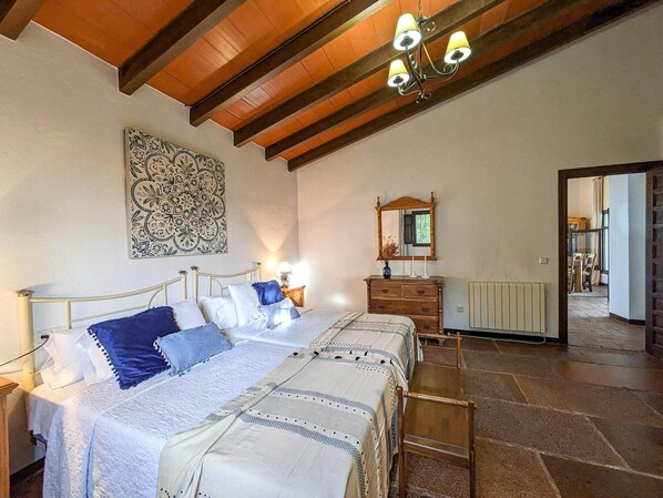 A bedroom with two beds, a wooden dresser, a mirror, and a chandelier. - Cottage in La Joya near El Torcal (La Joya)