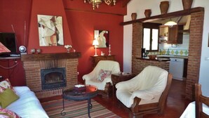 A cozy living room with a fireplace, a sofa, a chair, and a small table. - Beautiful villa in Andalusia near the forest (La Joya)