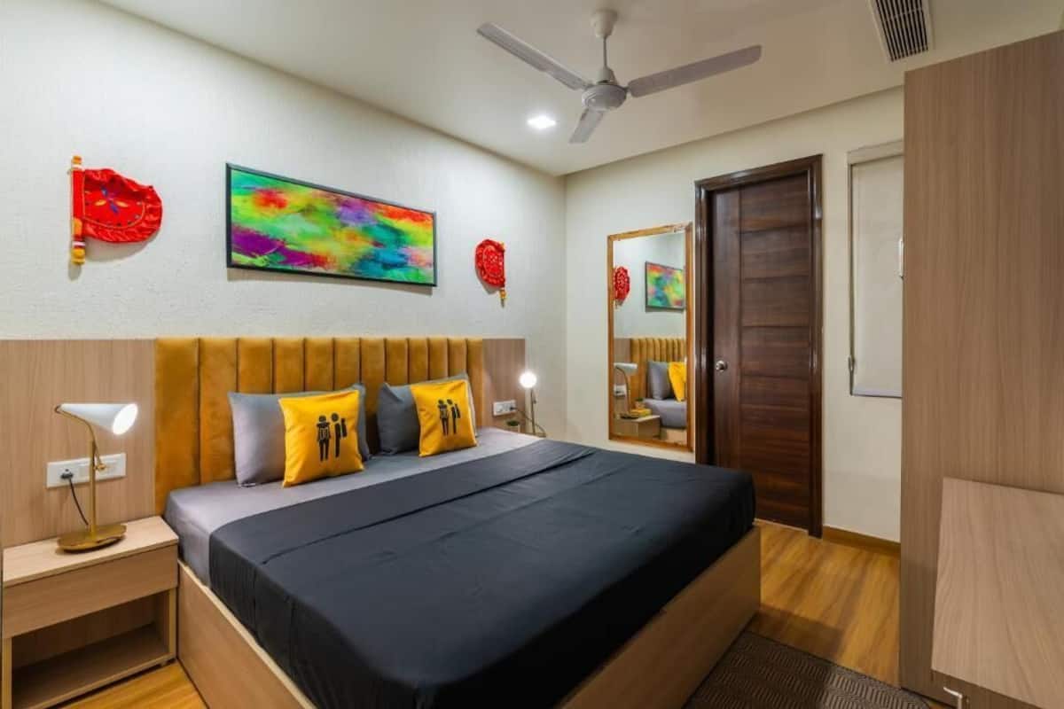 A hotel room with a bed, a nightstand, a ceiling fan, and a door.