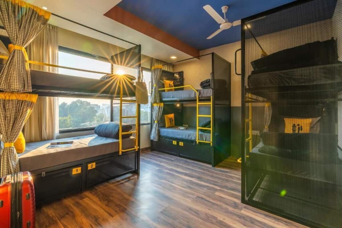 A room with bunk beds, a desk, and a window with curtains.