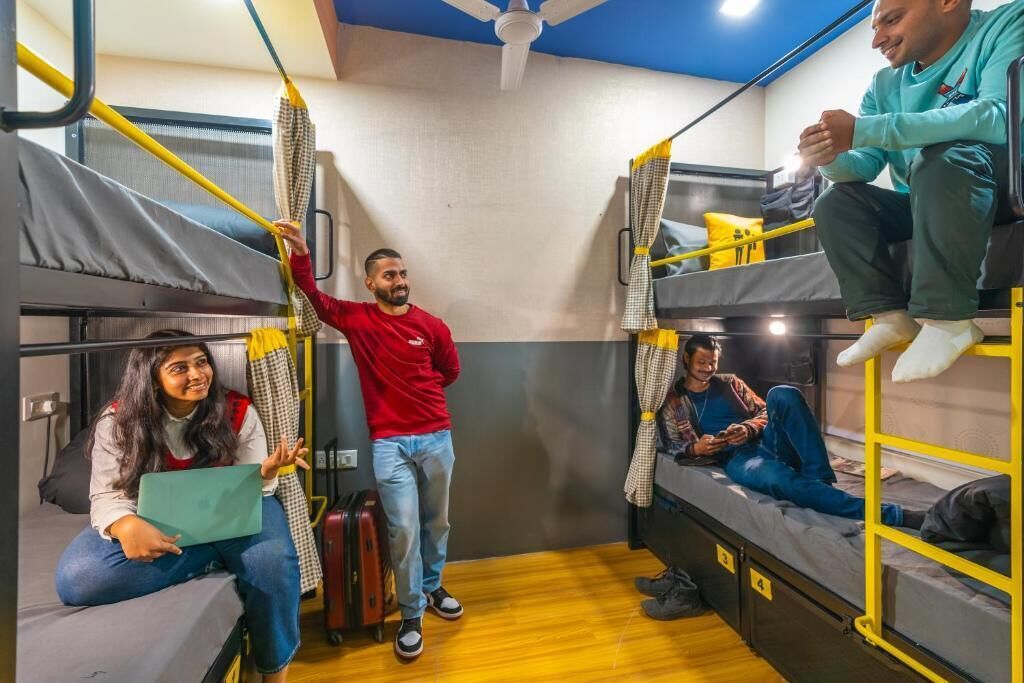 A dormitory room with bunk beds, a ceiling fan, and a suitcase on the floor.