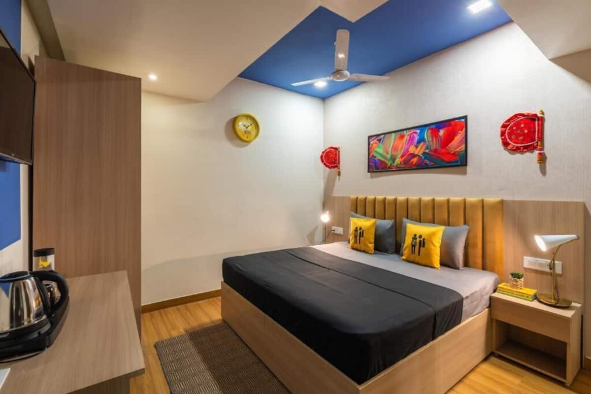 A modern bedroom with a bed, bedside tables, a ceiling fan, a clock, and a painting on the wall.