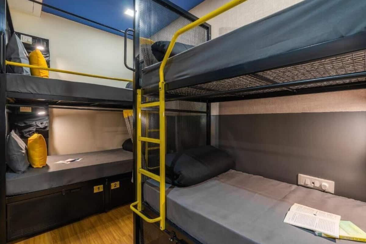 A bunk bed room with a ladder, storage compartments, and a power outlet.