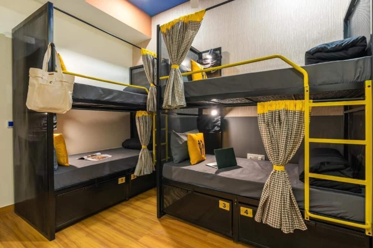 A dormitory room with bunk beds, a desk, and a chair.